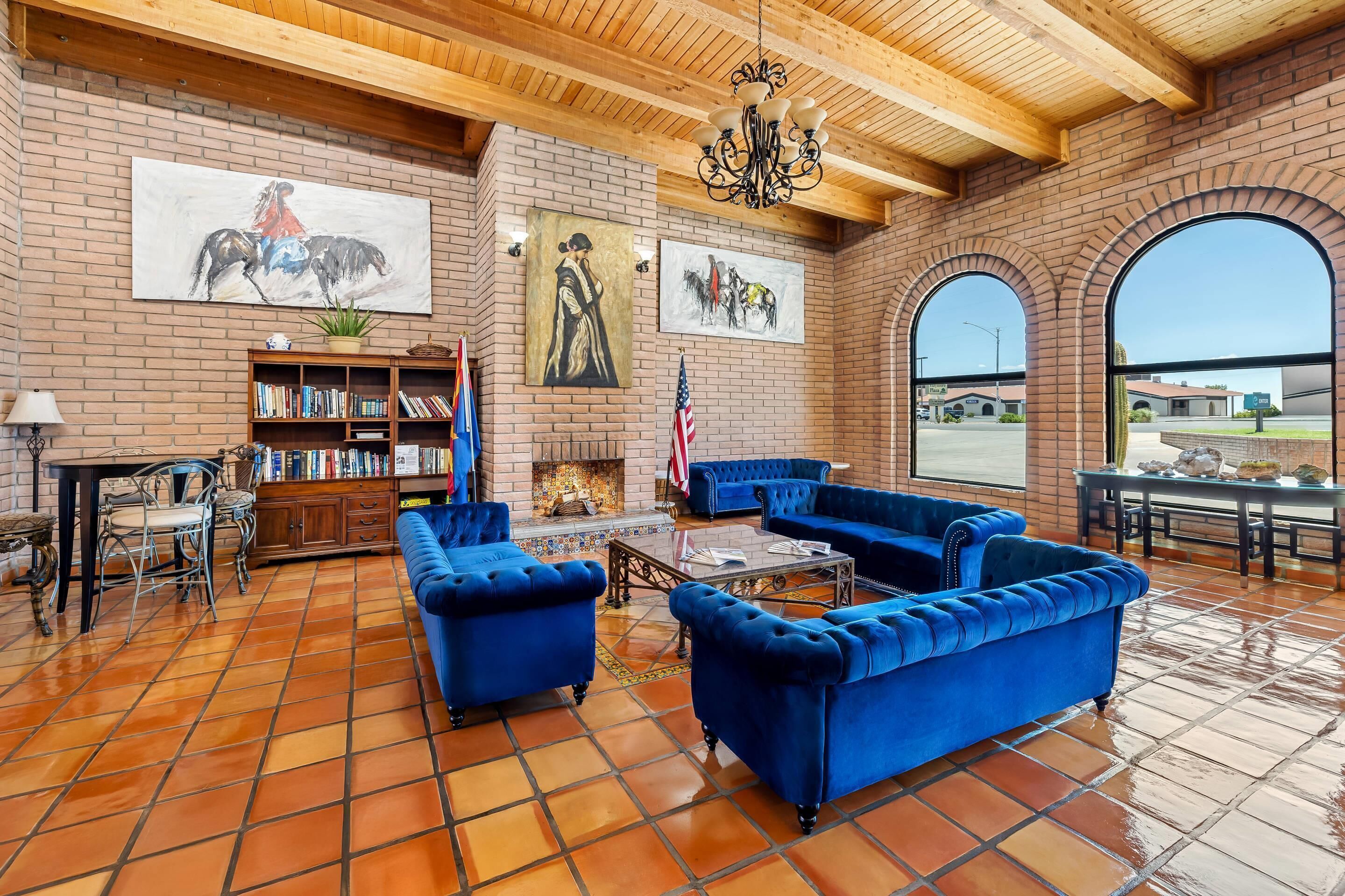 Un salon spacieux avec des canapés bleus, une cheminée, une bibliothèque et de grandes fenêtres.