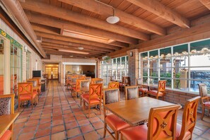 A restaurant with wooden tables and chairs, a tiled floor, and large windows. - Clarion Inn Sierra Vista near Ft. Huachuca (Sierra Vista)