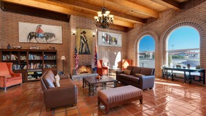 A spacious living room with a fireplace, leather furniture, and a large window overlooking a parking area. - Clarion Inn Sierra Vista near Ft. Huachuca (Sierra Vista)