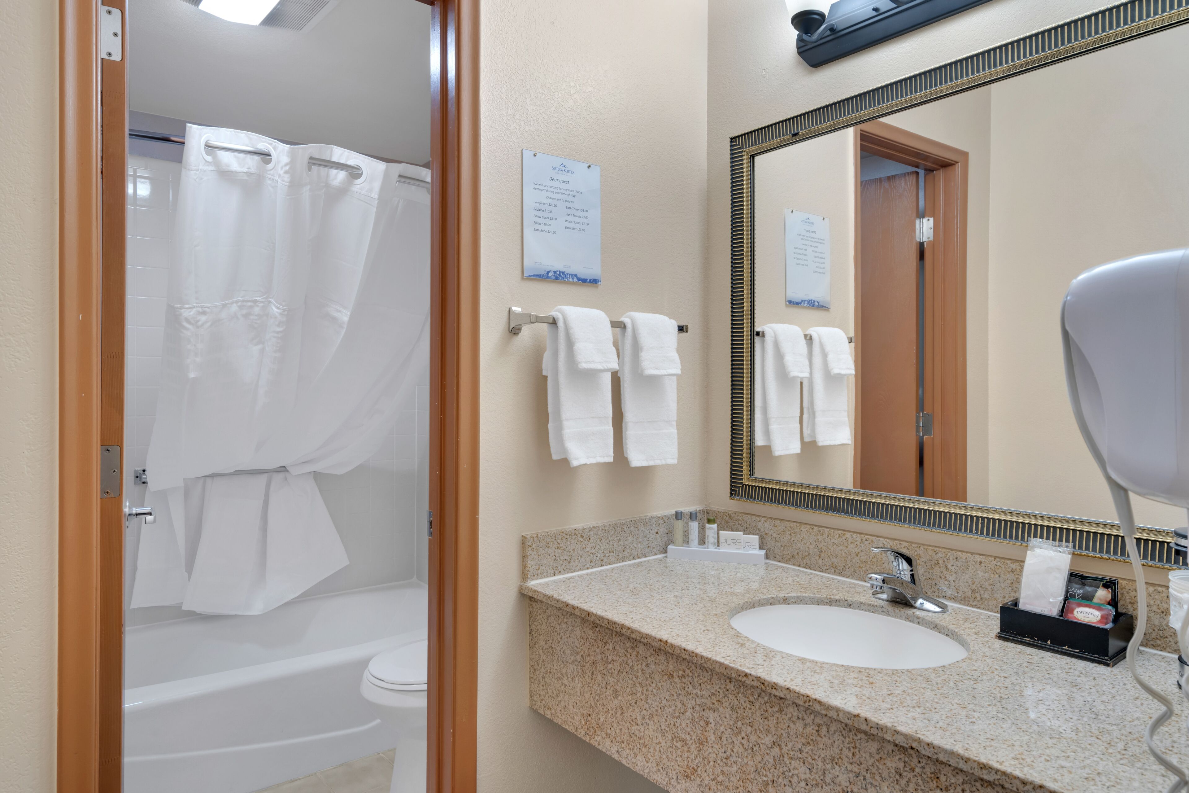 A bathroom with a shower, toilet, sink, and a large mirror.