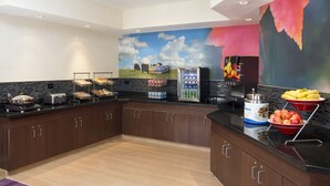 A modern kitchen with a black countertop, stainless steel appliances, and a mural of a landscape.