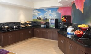 A modern kitchen with a black countertop, stainless steel appliances, and a mural of a landscape.