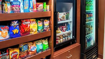 A snack display with various packaged foods and a refrigerator with beverages.