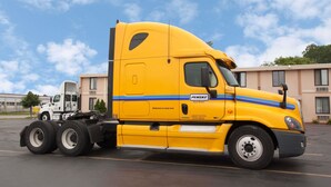 A yellow Penske truck parked in a lot with buildings in the background. - Super 8 by Wyndham Chicago Northlake O'Hare South (Northlake)