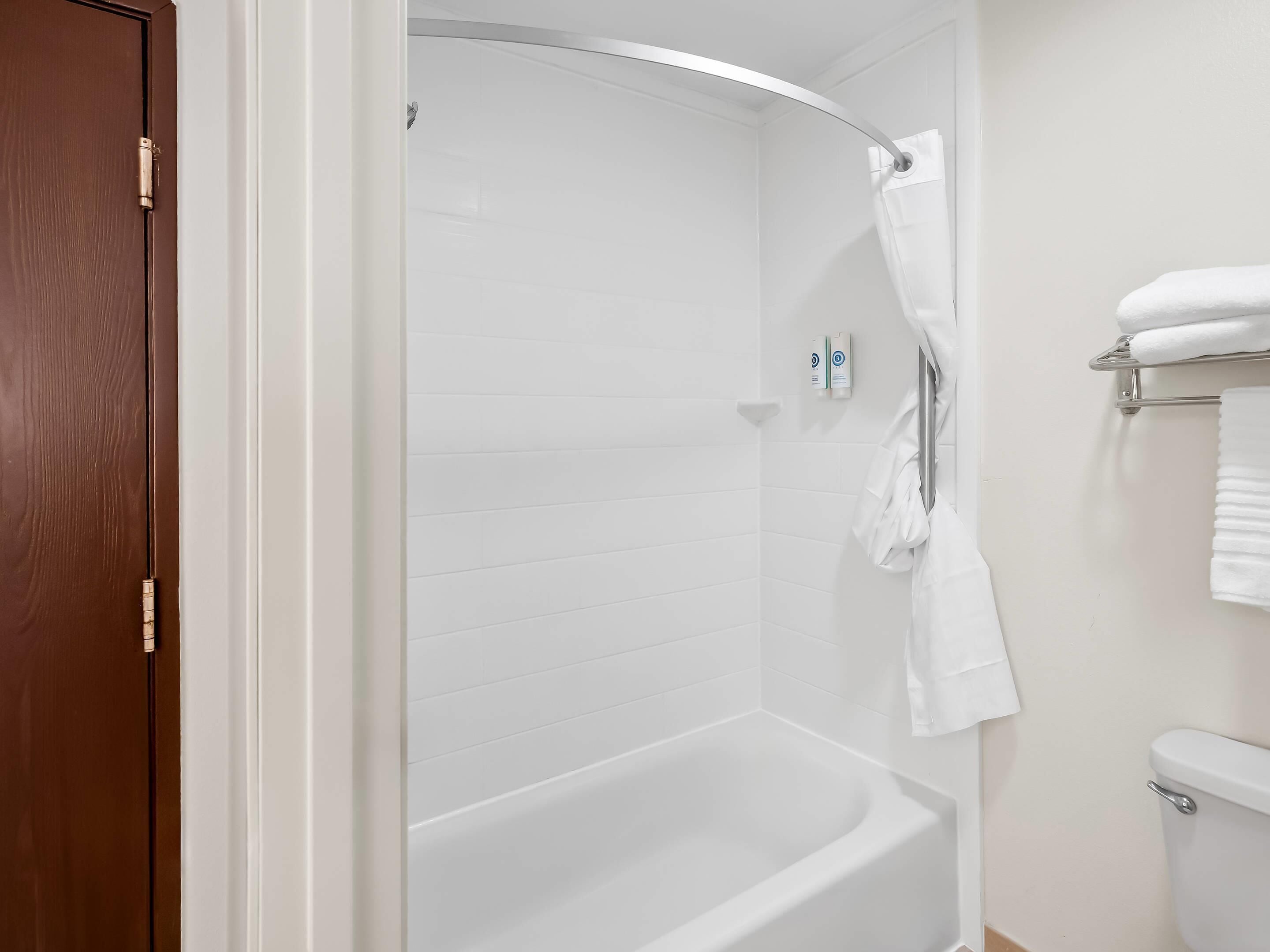 A modern bathroom with a white bathtub, a shower, and a toilet.