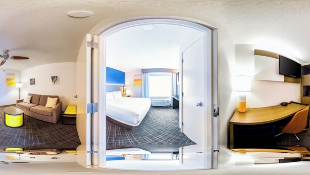 Ein modernes Hotelzimmer mit Bett, Sofa, Schreibtisch und Deckenventilator.