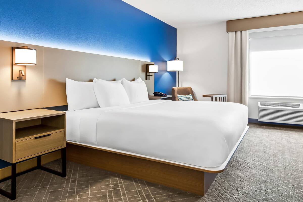 A hotel room with a large bed, bedside tables, a desk, and a chair.