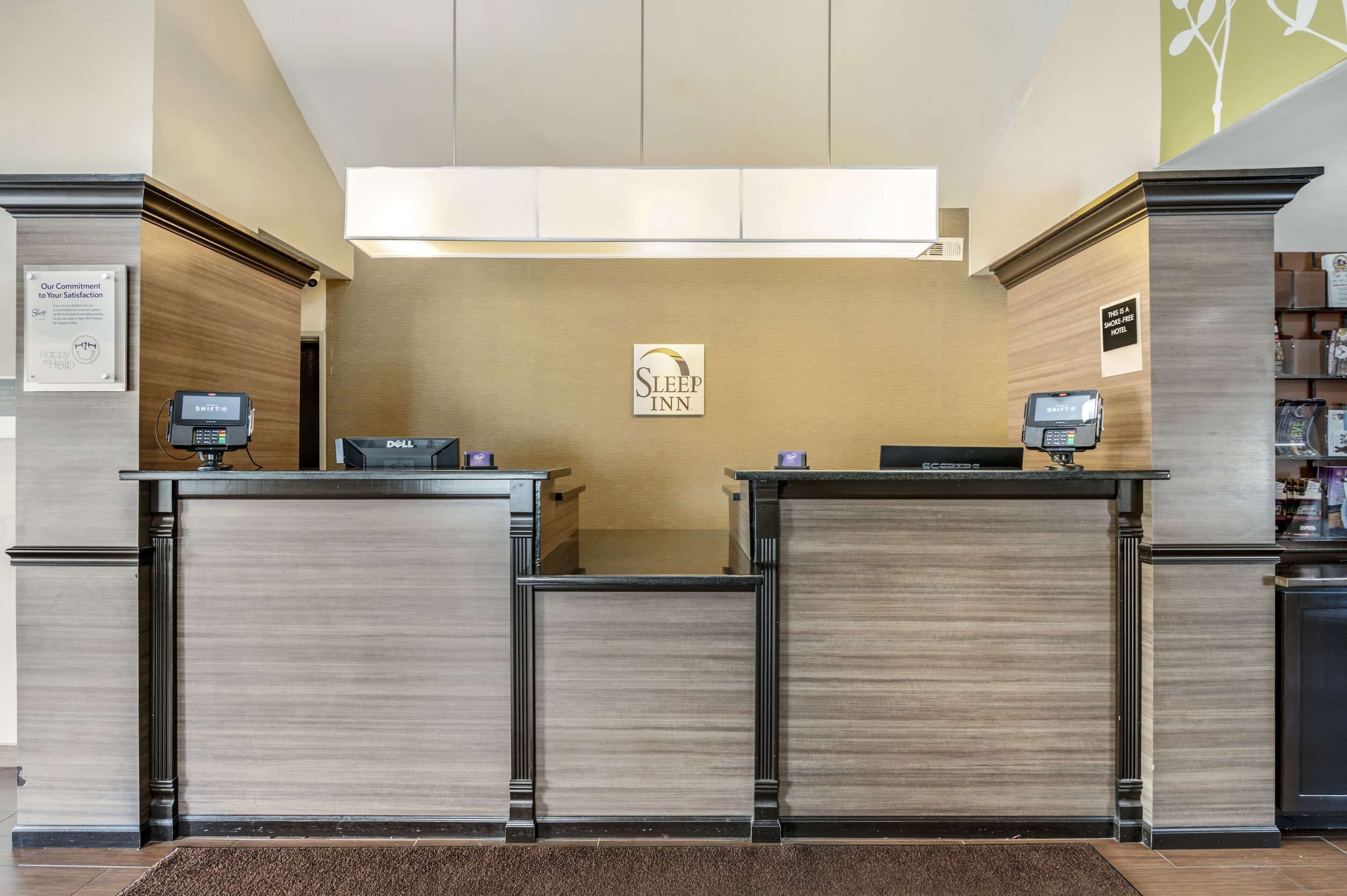 A hotel reception desk with a 'Sleep Inn' sign, a 'Shifts' machine, and a 'DELL' computer.