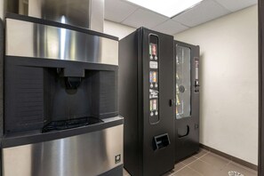 A commercial kitchen with stainless steel appliances, including a coffee machine and a refrigerator with beverage dispensers.