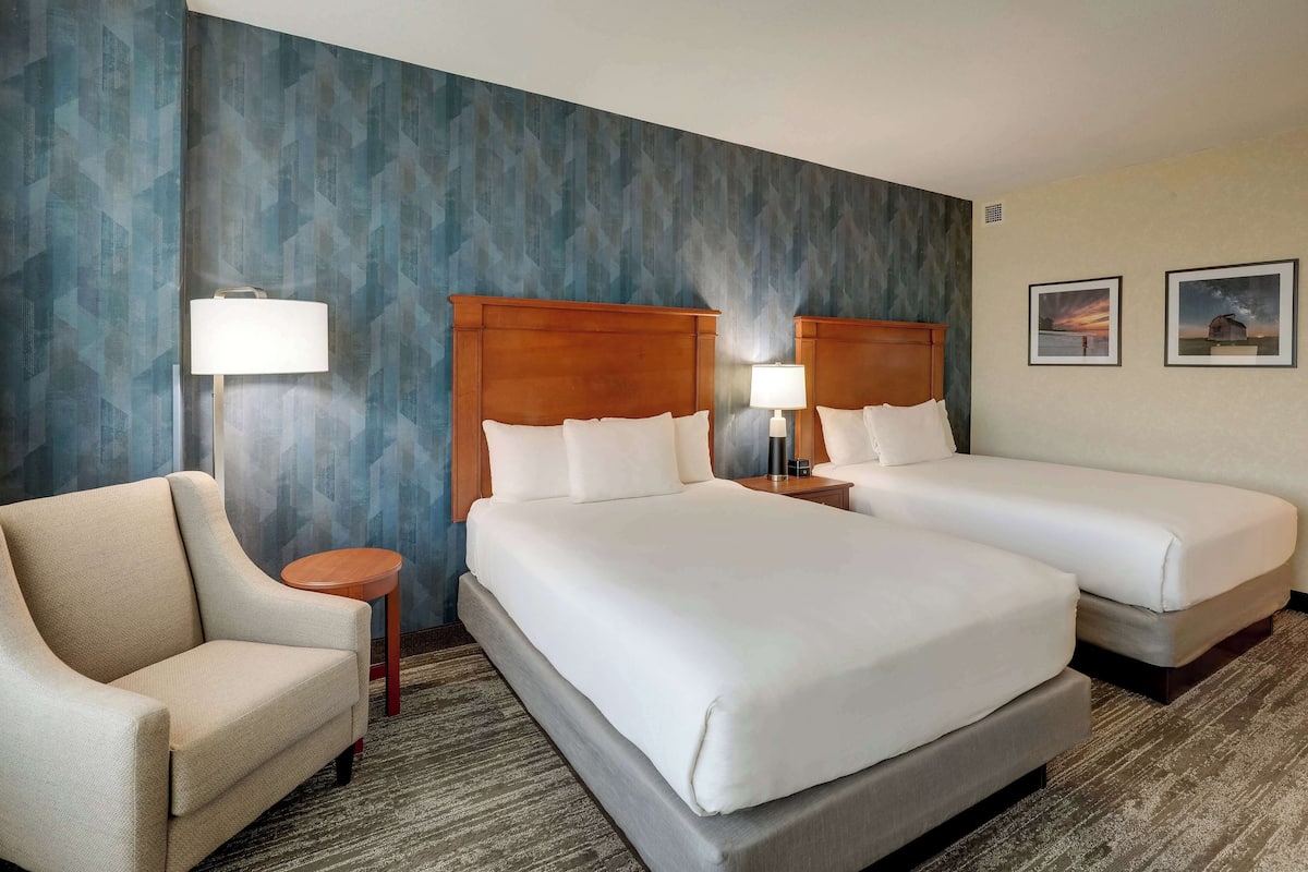 A hotel room with two beds, a sofa, and a small table.