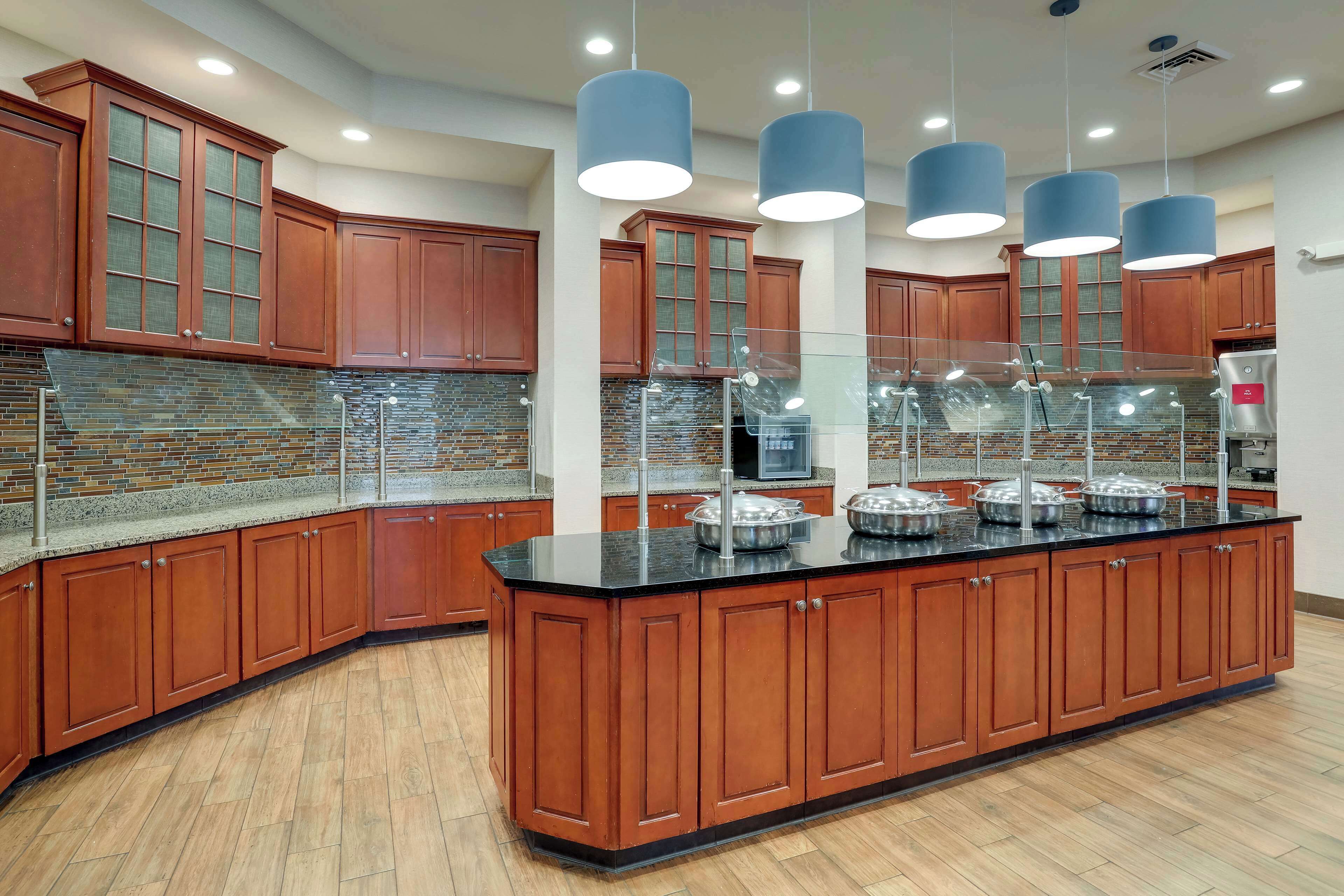 A modern kitchen with wooden cabinets, a granite countertop, and a central island with food display.