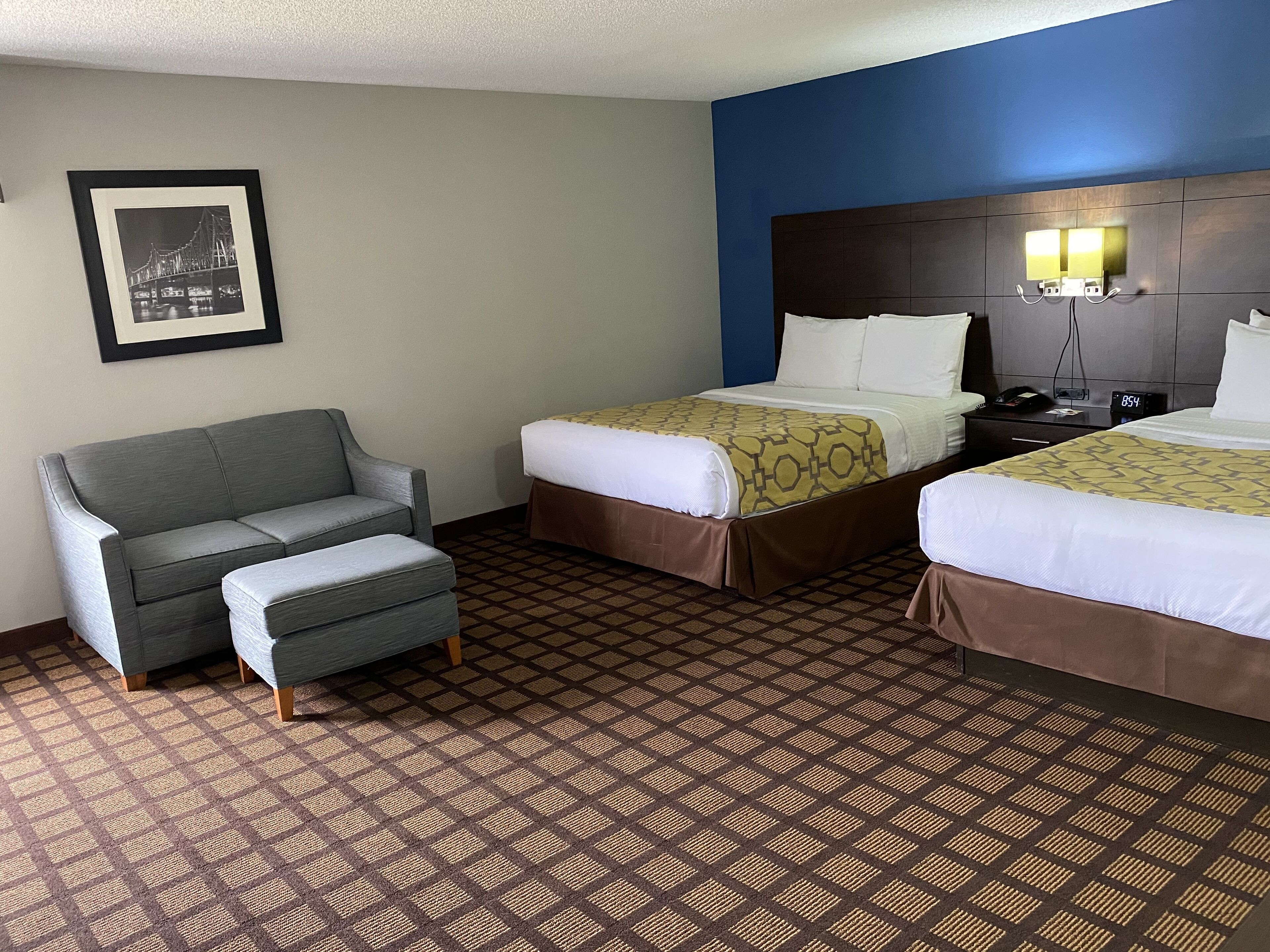 Une chambre d’hôtel avec deux lits, un canapé et une table de chevet.