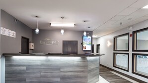A reception area with a grey reception desk, pendant lights, a sign reading "Baymont," and a window with a view. - Baymont by Wyndham Morton (Morton)