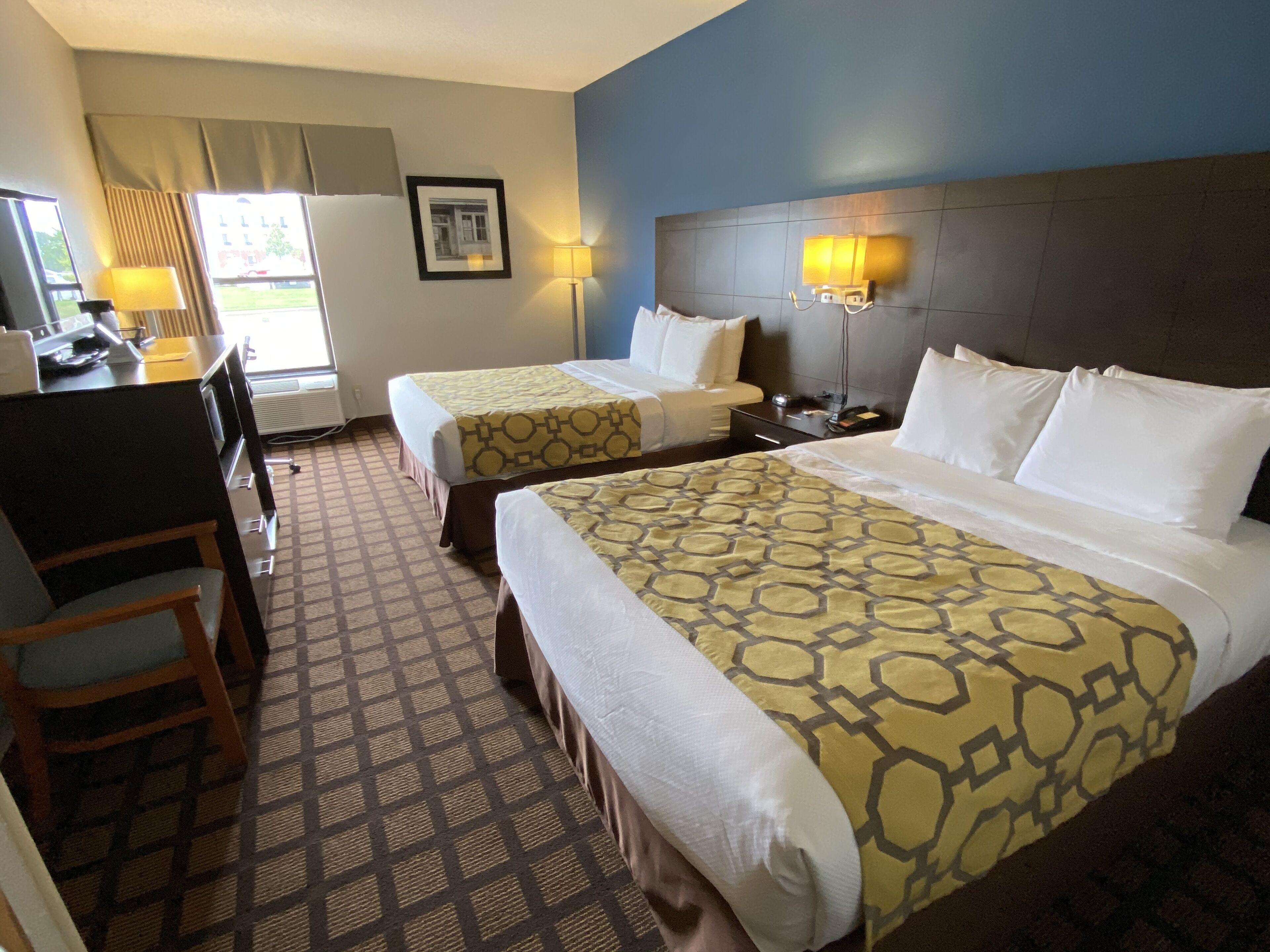 Une chambre d’hôtel avec deux lits, un bureau et une chaise.