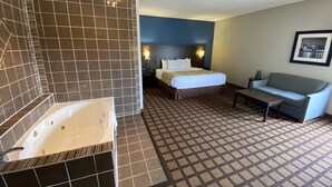A hotel room with a large bathtub, a bed with a headboard, a sofa, and a patterned floor. - Baymont by Wyndham Morton (Morton)