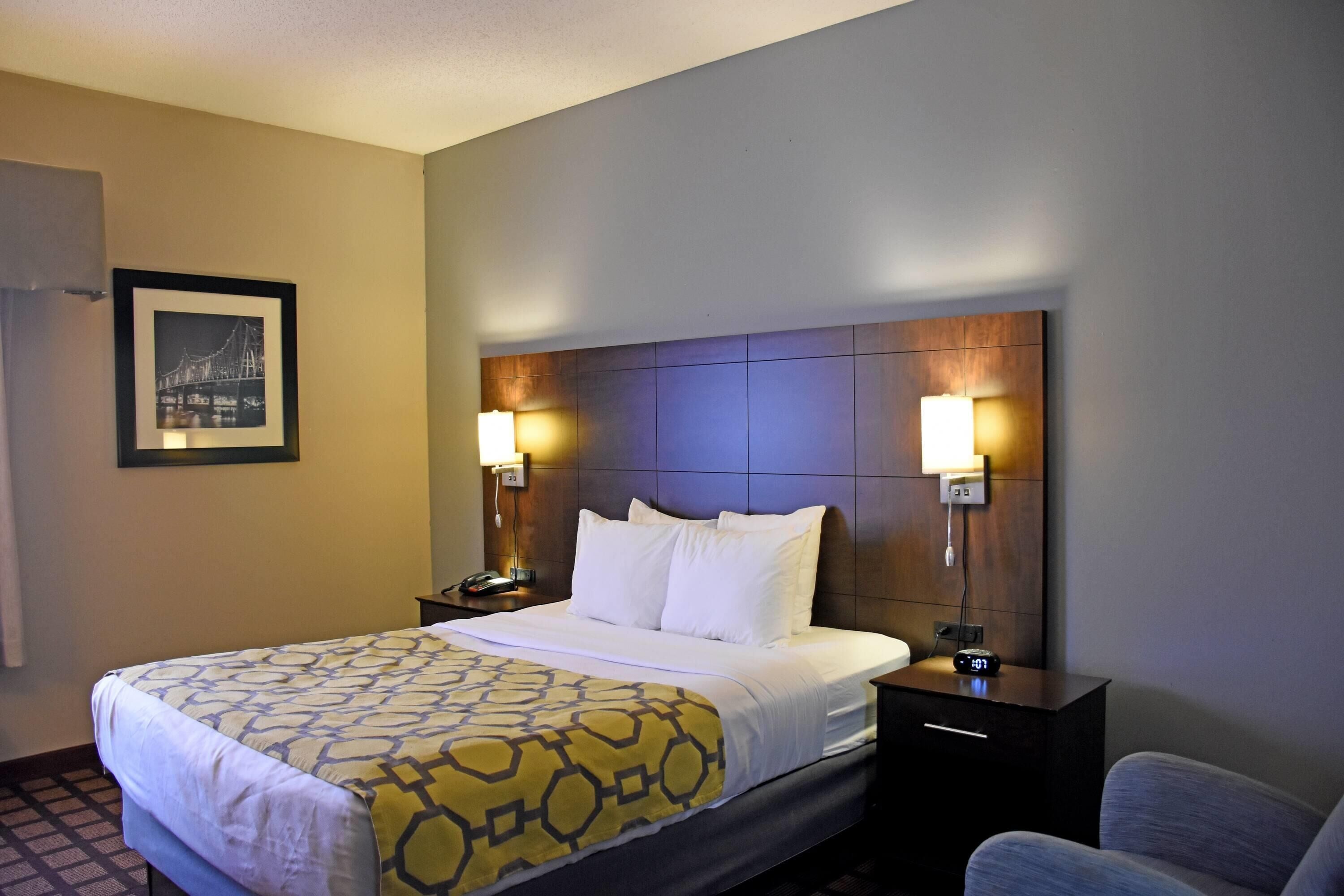 A hotel room with a large bed, two bedside lamps, a nightstand, and a chair.