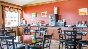 Ein Restaurant mit roter Wand, einer Theke mit Kaffeemaschine und mehreren Tischen und Stühlen.