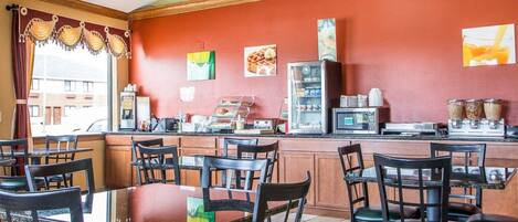 A restaurant with a red wall, a counter with a coffee machine, and several tables and chairs.