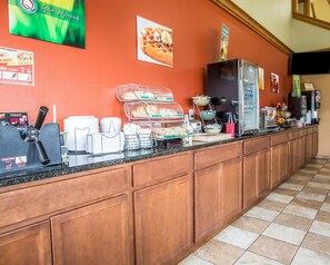 A breakfast bar with a coffee machine, a waffle display, and a refrigerator.