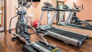 Ein Fitnessstudio mit Laufbändern, Crosstrainern und einem Ergometer.