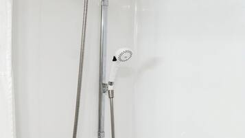 A shower with a handheld showerhead and a wall-mounted faucet.