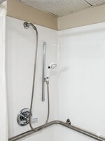 A shower with a handheld showerhead and a wall-mounted faucet.