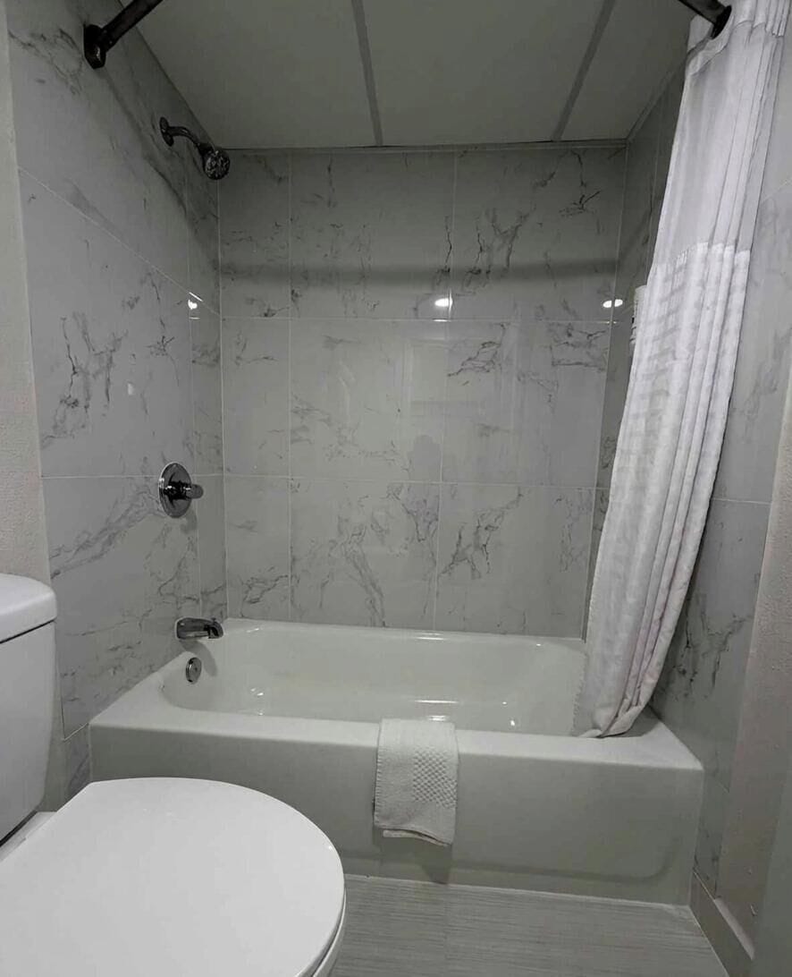 A bathroom with a bathtub, toilet, and shower curtain.