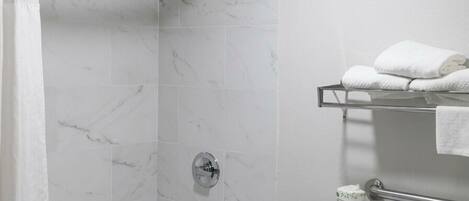 A bathroom with a bathtub, toilet, shower, and a towel rack.