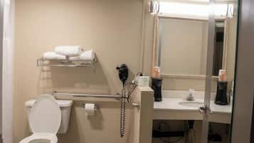 Un baño con inodoro, secamanos, toallero, lavamanos y espejo.