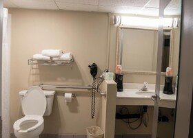 Un baño con inodoro, secamanos, toallero, lavamanos y espejo.