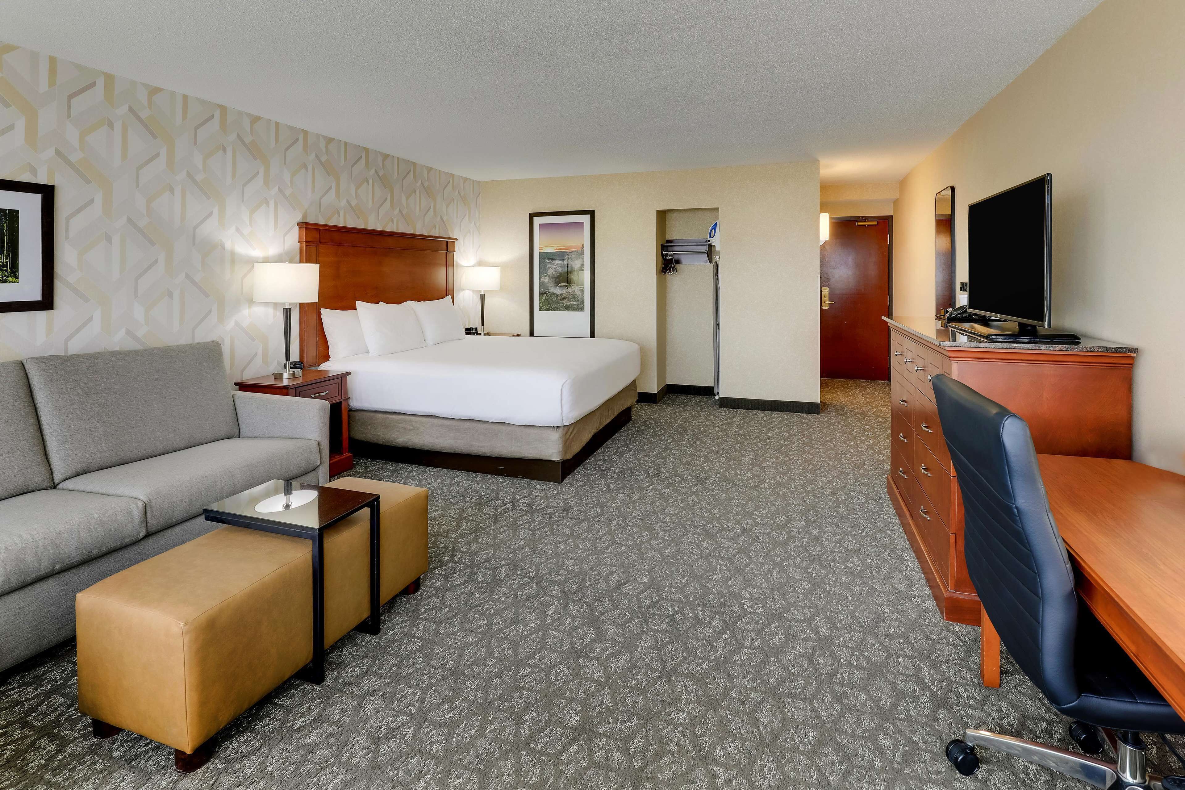Une chambre d’hôtel avec un lit, un canapé, un bureau et une télévision.