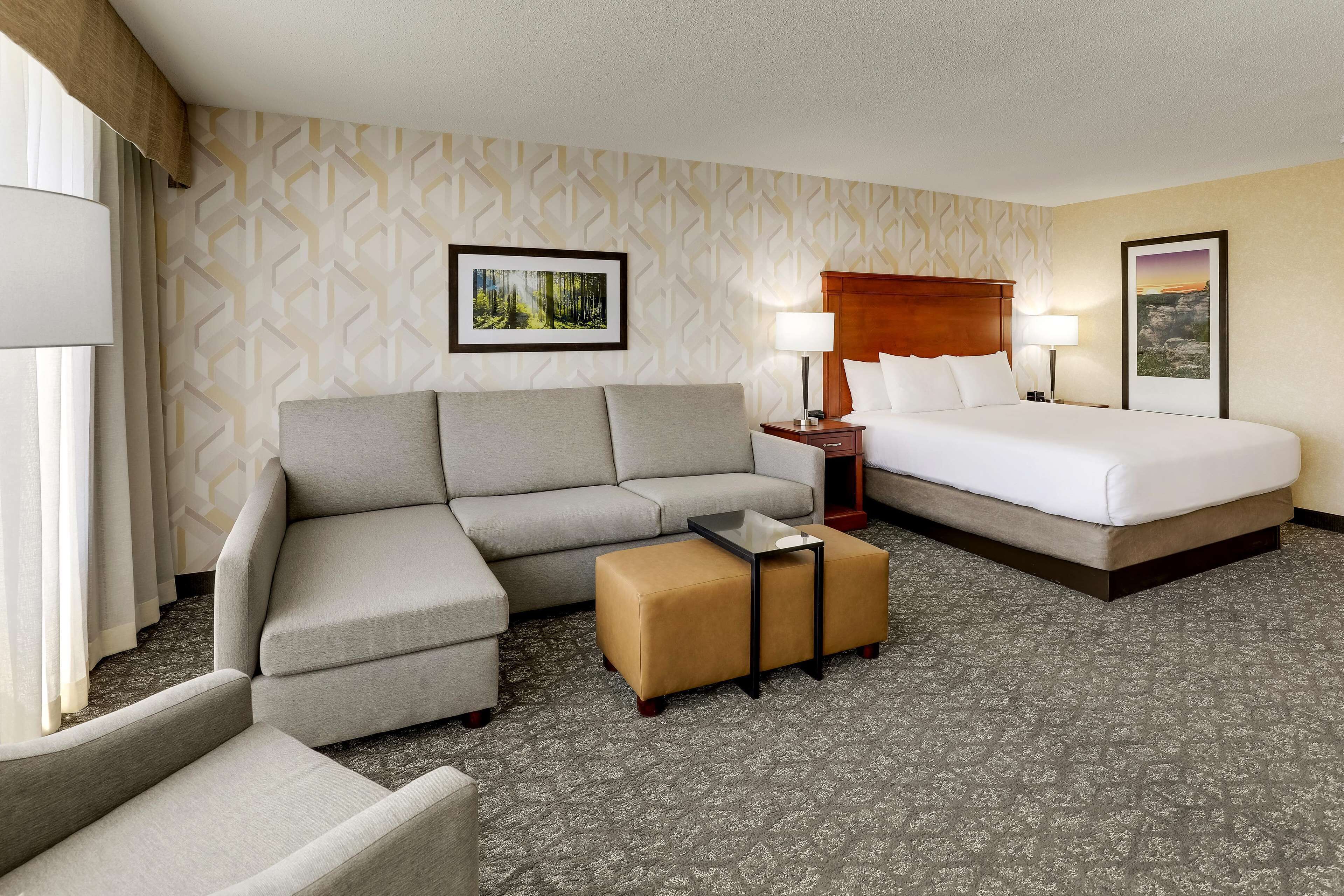 Una habitación de hotel con sofá, cama, mesita de noche y mesa de centro.