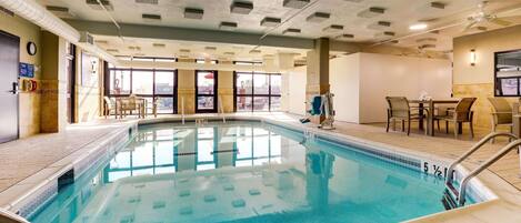Una piscina interior con agua cristalina, paredes de azulejos y un techo con rejillas cuadradas.