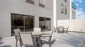An outdoor patio with a table and chairs, a white fence, and a building with large windows. - Best Western Heartland Inn (Mattoon)