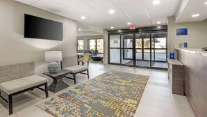 A modern lobby with a reception desk, seating area, and a large flat-screen TV mounted on the wall. - Best Western Heartland Inn (Mattoon)