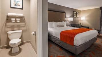 A hotel room with a bed, a bathroom, and a nightstand with a lamp.