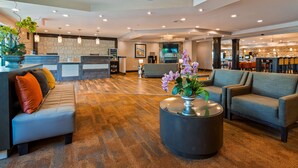 A modern lobby with a reception desk, seating area, and a bar.