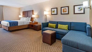 A hotel room with a bed, a sofa, a coffee table, a desk, and lamps. - Holiday Inn Express Lincoln (Lincoln)