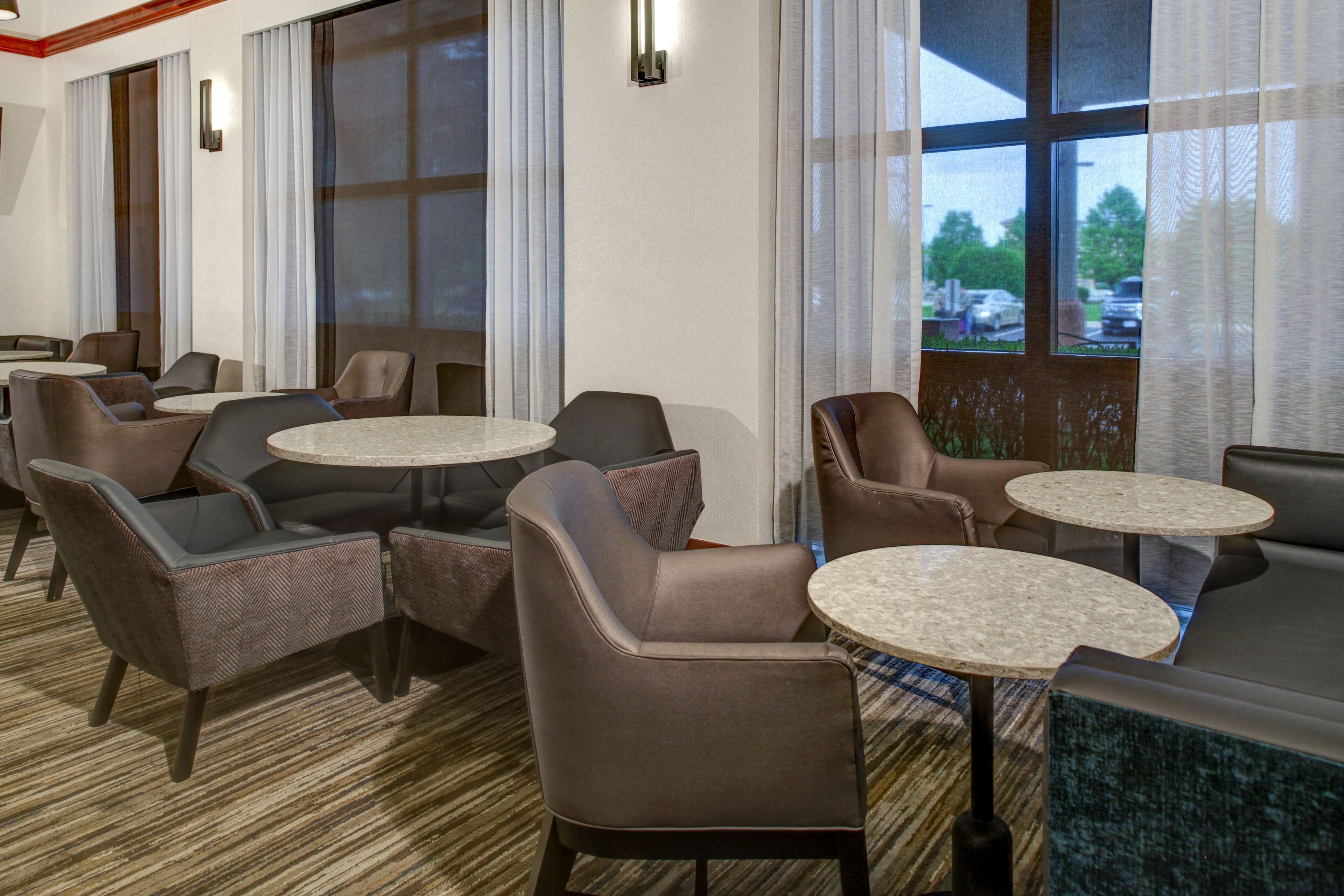 A hotel lobby with multiple seating areas, including sofas and chairs, arranged around small round tables.