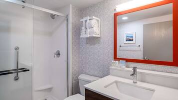 A modern bathroom with a glass shower enclosure, a white toilet, and a vanity with a large mirror.