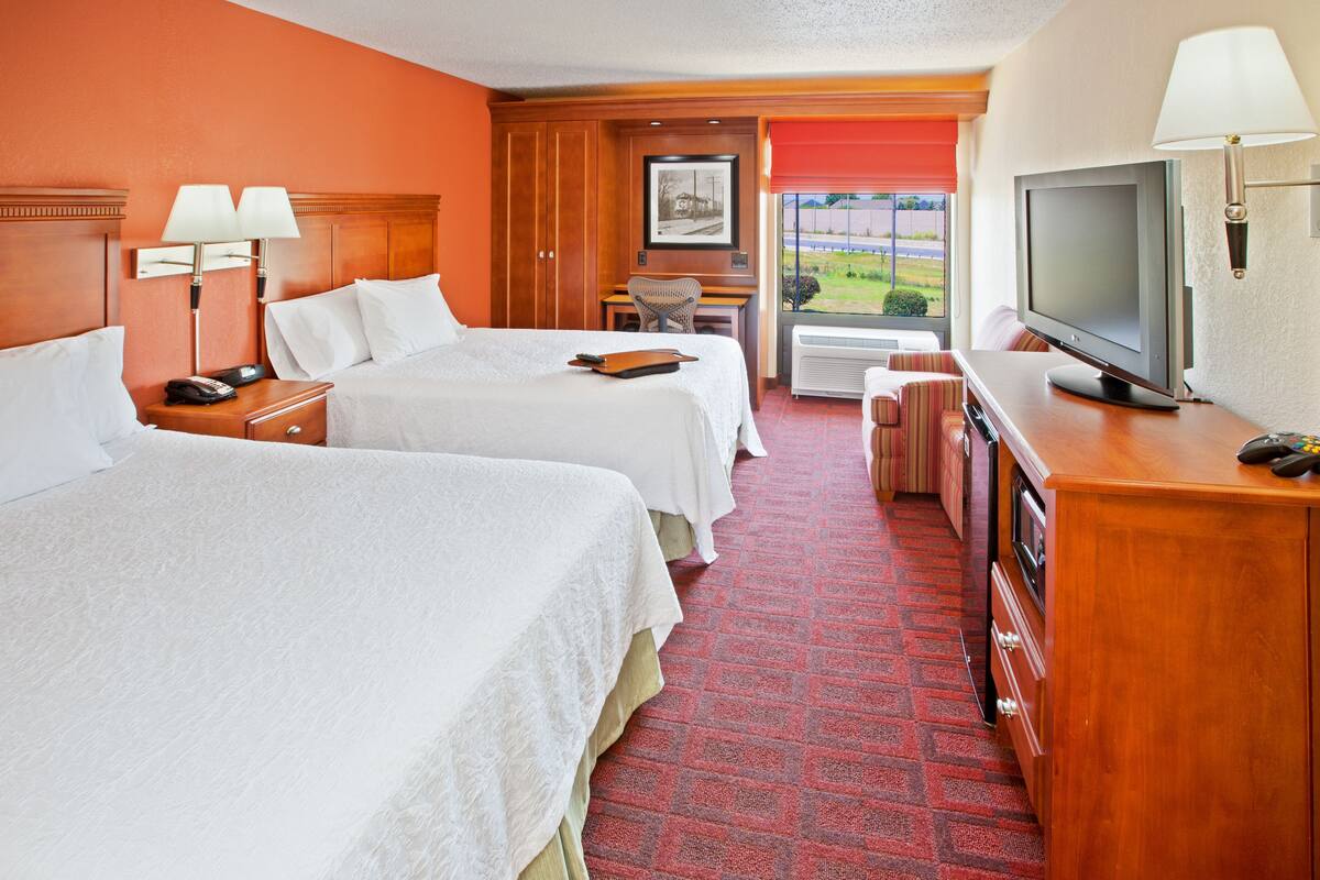 Een hotelkamer met twee bedden, een bureau, een televisie en een raam met uitzicht.