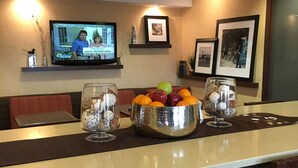 Zona de bar d'hotel amb barra, seients i un televisió que mostra un programa d'actualitat.