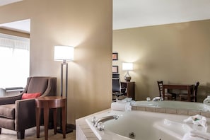 A hotel bathroom with a large bathtub, a chair, a small table, and a floor lamp. - Comfort Suites Effingham Central (Effingham)