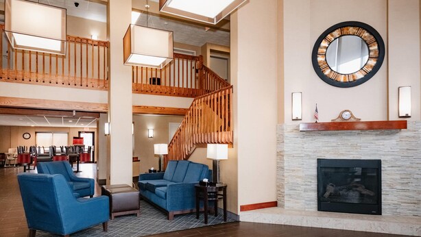 A spacious lobby with a fireplace, a staircase, and seating areas.