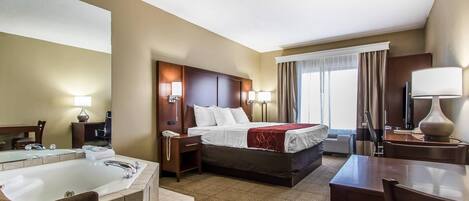 A hotel room with a large bed, a separate bathroom with a bathtub, a desk, and a chair.
