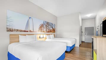 Habitación de hotel con dos camas, cabecero de madera, un escritorio con silla y un ventanal grande.