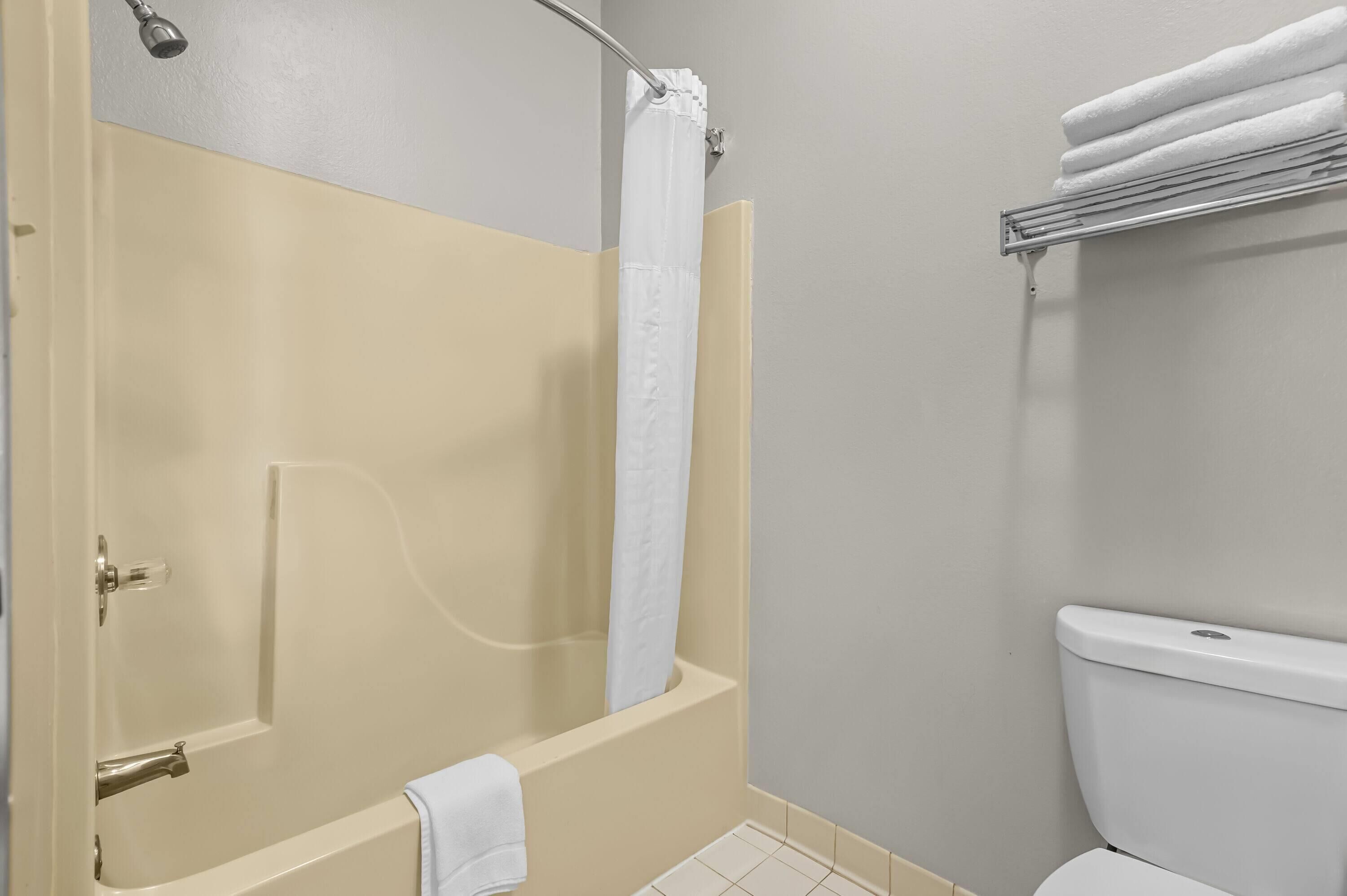 A bathroom with a bathtub, toilet, and towel rack.