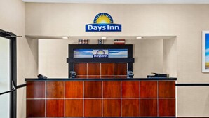 A reception desk with a Days Inn logo, a digital screen, and a telephone. - Days Inn by Wyndham Collinsville/St. Louis (Collinsville)