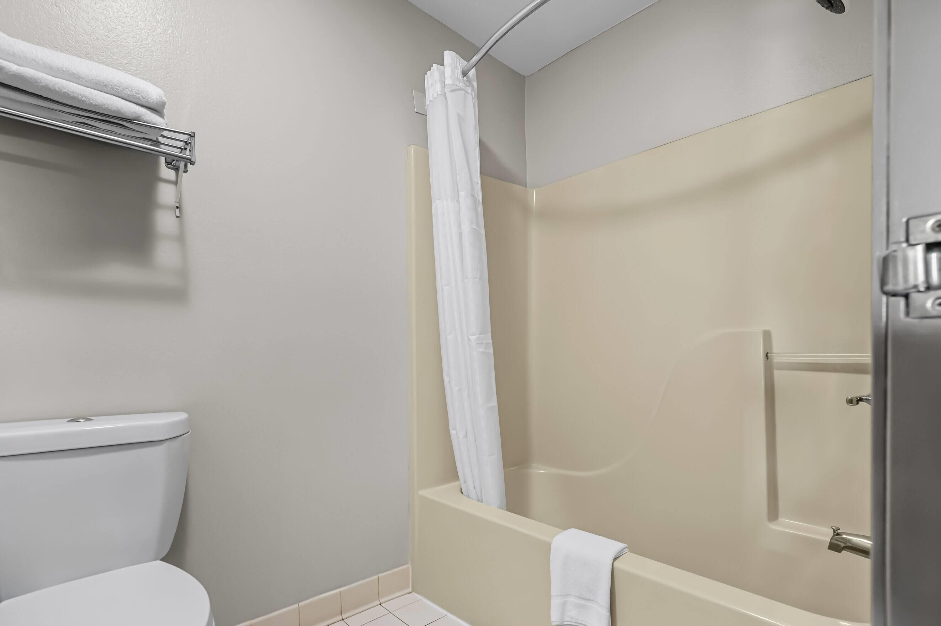 Un baño con inodoro, ducha con puerta de cristal y un perchero para toallas.