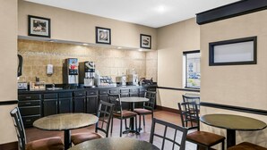A modern hotel lobby with a kitchen area, multiple seating arrangements, and framed artwork on the walls. - Days Inn by Wyndham Collinsville/St. Louis (Collinsville)